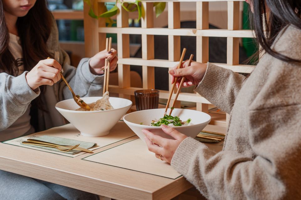 Due ospiti mangiano il phở con le bacchette
